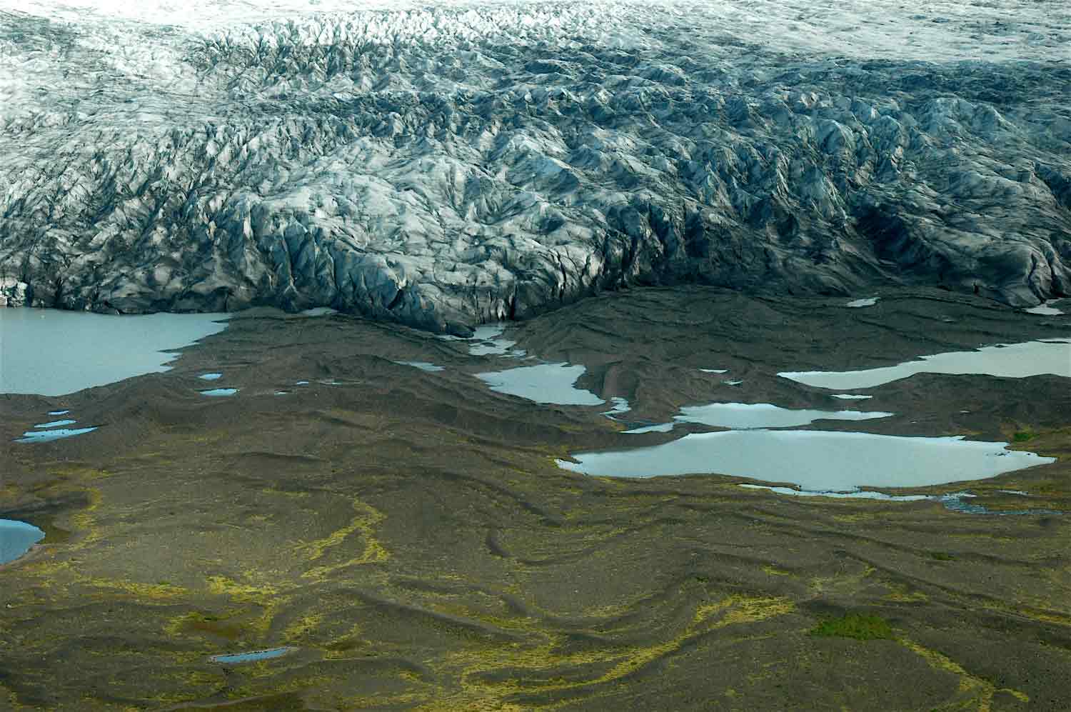 A large glacier and a rocky landscape with lakes.