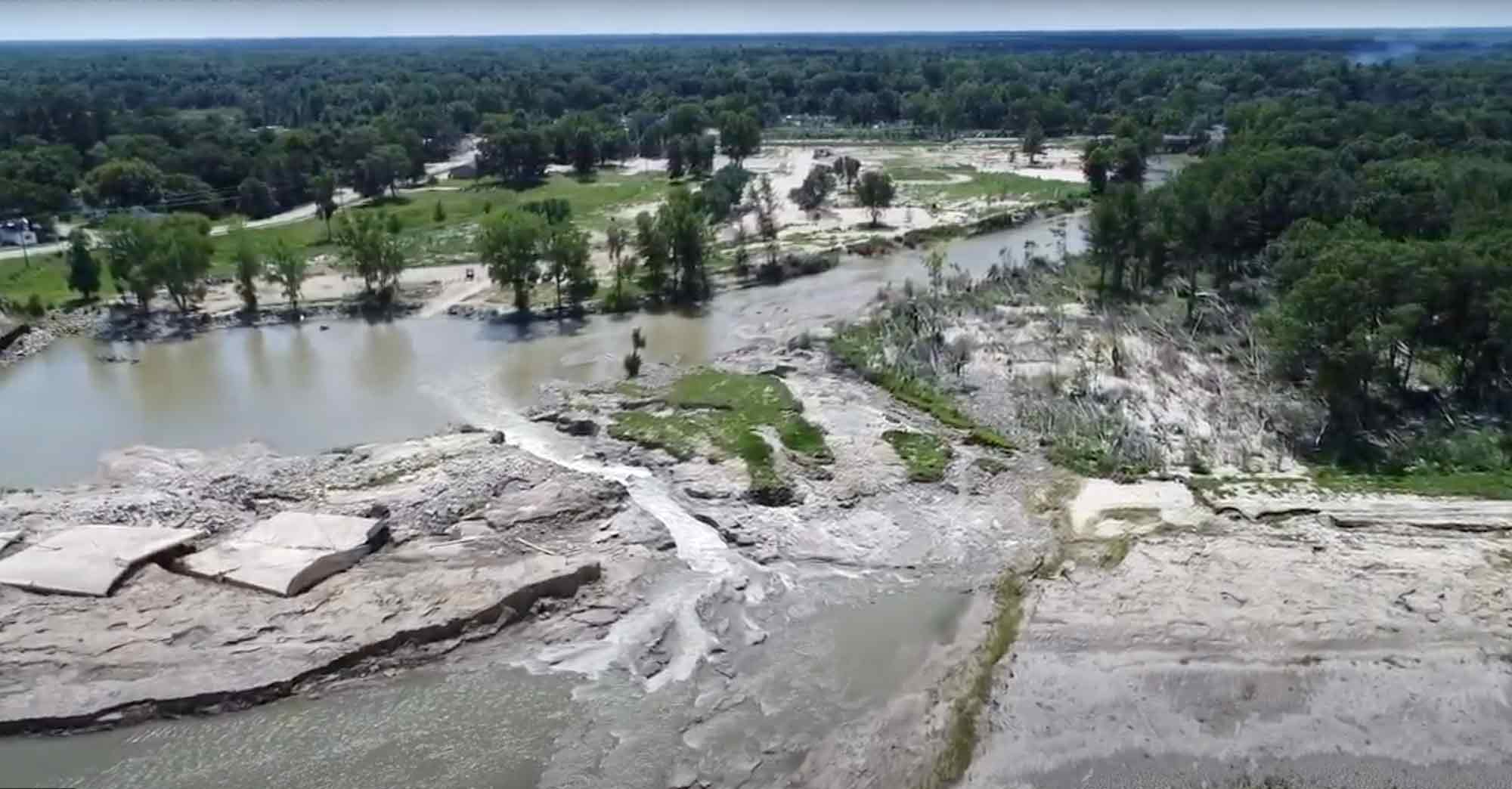 An aerial view of a broken dam and flooded river.